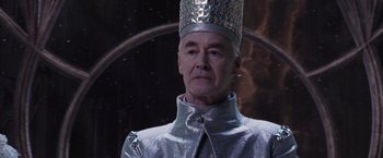 Movie still from “Jupiter Ascending” (2015), directed by Lilly Wachowski – An older man wearing a silver outfit and a crown; Close Up shot, Low angle