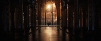 Movie still from “Jupiter Ascending” (2015), directed by Lilly Wachowski – A person sitting on a bench in front of a large window; Extreme Wide shot, High angle