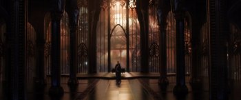 Movie still from “Jupiter Ascending” (2015), directed by Lilly Wachowski – A man sitting on a bench in front of a large window; Extreme Wide shot, High angle