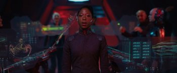 Movie still from “Jupiter Ascending” (2015), directed by Lilly Wachowski – A woman standing in front of a group of people; Medium shot, Over the shoulder angle