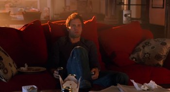 Movie still from “Just Like Heaven” (2005), directed by Mark Waters – A man sitting on top of a red couch holding a wii controller; Wide shot, High angle