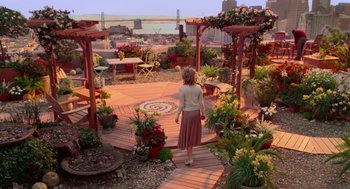 Movie still from “Just Like Heaven” (2005), directed by Mark Waters – A woman is walking on a deck surrounded by flowers; Wide shot, High angle