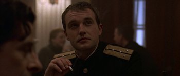 Movie still from “K-19: The Widowmaker” (2002), directed by Kathryn Bigelow – A person wearing a uniform holding a cigarette; Close Up shot, Low angle