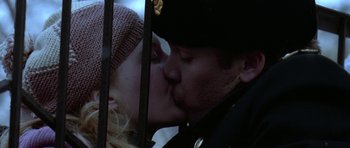 Movie still from “K-19: The Widowmaker” (2002), directed by Kathryn Bigelow – A man and a woman kissing in front of an iron fence; Close Up shot, Low angle