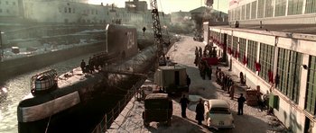 Movie still from “K-19: The Widowmaker” (2002), directed by Kathryn Bigelow – A group of people standing next to a boat on the water; Extreme Wide shot, High angle