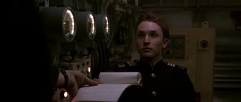 Movie still from “K-19: The Widowmaker” (2002), directed by Kathryn Bigelow – A man in a military uniform holding a book; Close Up shot, Low angle