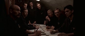Movie still from “K-19: The Widowmaker” (2002), directed by Kathryn Bigelow – A group of men sitting at a table with papers on top of it; Medium shot, High angle