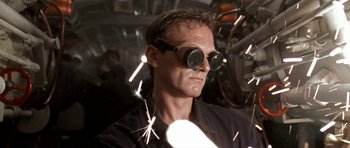 Movie still from “K-19: The Widowmaker” (2002), directed by Kathryn Bigelow – A man wearing protective goggles while welding a piece of metal; Close Up shot, Low angle