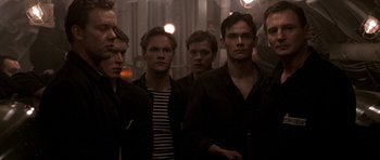 Movie still from “K-19: The Widowmaker” (2002), directed by Kathryn Bigelow – A group of men standing next to each other in a dark room; Medium shot, Over the shoulder angle