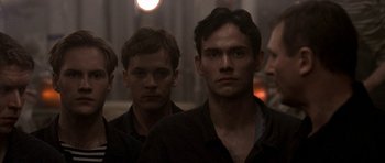 Movie still from “K-19: The Widowmaker” (2002), directed by Kathryn Bigelow – A group of men standing next to each other in a room; Close Up shot, Over the shoulder angle