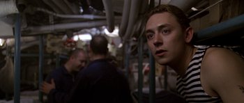 Movie still from “K-19: The Widowmaker” (2002), directed by Kathryn Bigelow – A young man is looking into the camera while standing on a train; Close Up shot, Over the shoulder angle