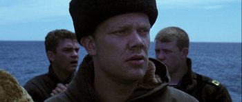 Movie still from “K-19: The Widowmaker” (2002), directed by Kathryn Bigelow – A person wearing a jacket and a hat; Close Up shot, Low angle