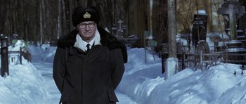 Movie still from “K-19: The Widowmaker” (2002), directed by Kathryn Bigelow – A man in a black coat and a hat standing in the snow; Medium shot, Low angle