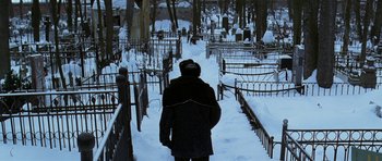 Movie still from “K-19: The Widowmaker” (2002), directed by Kathryn Bigelow – A man walking through a cemetery covered in snow; Wide shot, High angle