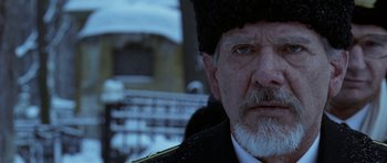 Movie still from “K-19: The Widowmaker” (2002), directed by Kathryn Bigelow – An old man with a beard wearing a fur hat; Close Up shot, Over the shoulder angle