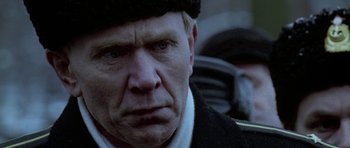 Movie still from “K-19: The Widowmaker” (2002), directed by Kathryn Bigelow – An old man with a hat and a black jacket; Close Up shot, Over the shoulder angle