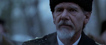 Movie still from “K-19: The Widowmaker” (2002), directed by Kathryn Bigelow – An old man with a beard wearing a black hat; Close Up shot, Over the shoulder angle