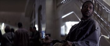 Movie still from “K-PAX” (2001), created by Robert Cochran – A person holding a cup of coffee in their hand; Close Up shot, Low angle