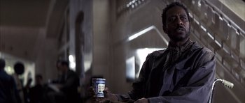 Movie still from “K-PAX” (2001), created by Robert Cochran – A man sitting at a table with a cup of coffee; Close Up shot, Low angle