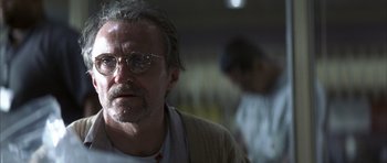 Movie still from “K-PAX” (2001), created by Robert Cochran – An older man wearing glasses and a white t - shirt; Close Up shot, Low angle