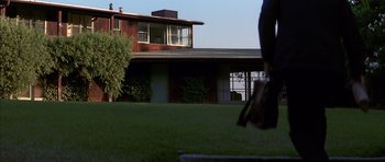 Movie still from “K-PAX” (2001), created by Robert Cochran – A person standing in the grass in front of a house; Extreme Wide shot, Low angle