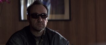 Movie still from “K-PAX” (2001), created by Robert Cochran – A person wearing a jacket and sunglasses; Close Up shot, Over the shoulder angle