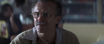 Movie still from “K-PAX” (2001), created by Robert Cochran – An older man wearing glasses and a shirt; Close Up shot, Low angle