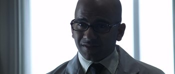 Movie still from “K-PAX” (2001), created by Robert Cochran – A bald man wearing glasses and a tie; Close Up shot, Low angle