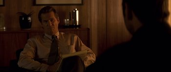 Movie still from “K-PAX” (2001), created by Robert Cochran – A man sitting in front of a mirror in a dimly - lit room; Close Up shot, Over the shoulder angle