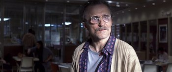 Movie still from “K-PAX” (2001), created by Robert Cochran – An older man wearing glasses and wearing a tie; Close Up shot, Over the shoulder angle