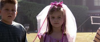 Movie still from “K-PAX” (2001), created by Robert Cochran – A little girl wearing a pink dress and a veil; Close Up shot, High angle