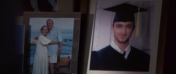 Movie still from “K-PAX” (2001), created by Robert Cochran – A picture of a man in a cap and gown and an older picture of himself; Extreme Close Up shot, High angle