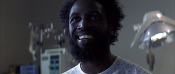 Movie still from “K-PAX” (2001), created by Robert Cochran – A person with a beard smiling; Close Up shot, Low angle