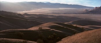 Movie still from “K-PAX” (2001), created by Robert Cochran – A view of a desert landscape from a hill top; Extreme Wide shot, High angle