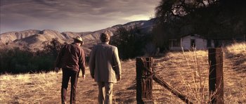 Movie still from “K-PAX” (2001), created by Robert Cochran – Two men are walking in a field near a wooden fence; Extreme Wide shot, High angle