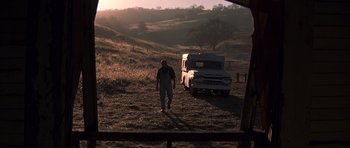 Movie still from “K-PAX” (2001), created by Robert Cochran – A man standing next to an old truck in a field; Wide shot, Low angle