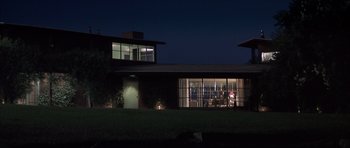 Movie still from “K-PAX” (2001), created by Robert Cochran – A building with a large window at night time; Extreme Wide shot, Low angle