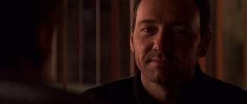 Movie still from “K-PAX” (2001), created by Robert Cochran – A man's face in a dark room; Close Up shot, Over the shoulder angle