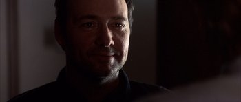 Movie still from “K-PAX” (2001), created by Robert Cochran – A man's face in a dark room; Close Up shot, Over the shoulder angle