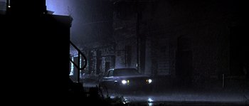 Movie still from “Kalifornia” (1993), directed by Dominic Sena – A car driving down a street in the rain; Extreme Wide shot, Low angle