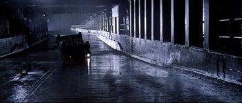 Movie still from “Kalifornia” (1993), directed by Dominic Sena – A car is parked in a parking lot in the rain; Extreme Wide shot, High angle