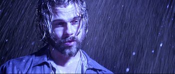 Movie still from “Kalifornia” (1993), directed by Dominic Sena – A man with a long beard standing in the pouring rain; Close Up shot, Low angle