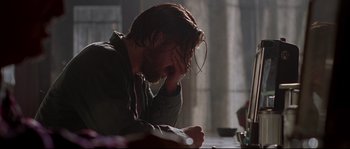 Movie still from “Kalifornia” (1993), directed by Dominic Sena – A man sitting at a table with his head in his hand; Close Up shot, Over the shoulder angle