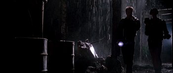 Movie still from “Kalifornia” (1993), directed by Dominic Sena – A light shines through a window in the rain; Wide shot, Low angle