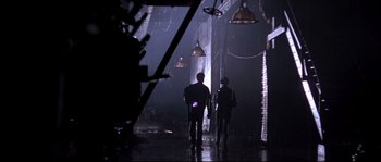 Movie still from “Kalifornia” (1993), directed by Dominic Sena – A group of people standing in a dark room; Wide shot, Low angle
