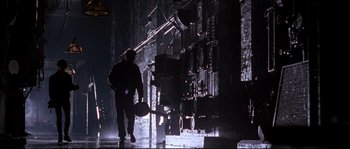 Movie still from “Kalifornia” (1993), directed by Dominic Sena – A man walking in the rain holding a shovel; Wide shot, Low angle