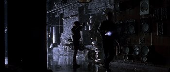 Movie still from “Kalifornia” (1993), directed by Dominic Sena – Two people in a dark room with lights on; Wide shot, Low angle