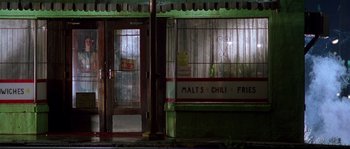 Movie still from “Kalifornia” (1993), directed by Dominic Sena – A store front at night lit by street lamps; Wide shot, Low angle