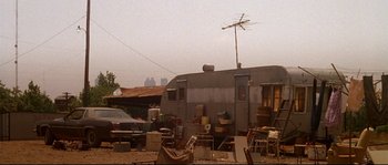 Movie still from “Kalifornia” (1993), directed by Dominic Sena – An old trailer parked in the middle of a dirt field; Wide shot, Low angle