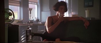 Movie still from “Kalifornia” (1993), directed by Dominic Sena – A woman sitting at a table with a glass of wine; Medium shot, Low angle